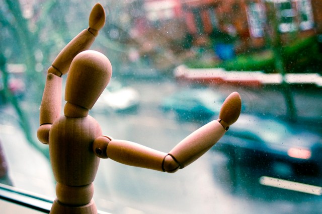 wooden human looking out window